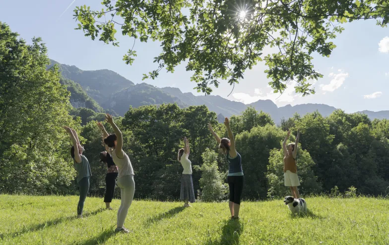 Grupo de personas haciendo estiramientos en plena naturaleza, un prado verde.