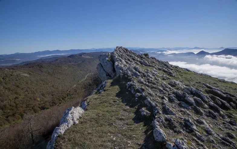 Cresta calcárea de la Sierra de Aralar con cortados rocosos, prados alpinos y vistas panorámicas hacia valles.
