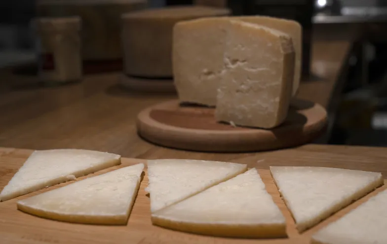 Queso artesanal cortado en cuñas sobre tabla de madera en quesería Ekia, Pirineo de Navarra.