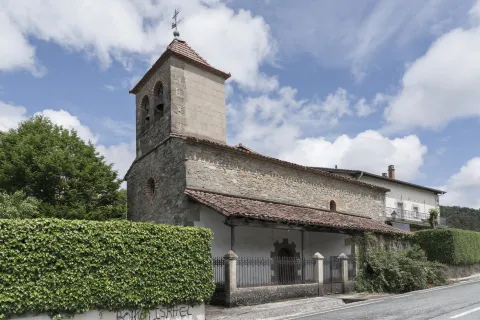 Iglesia parroquial romanica de piedra con torre campanario en Agorreta, Pirineo navarro, rodeada de vegetacion.