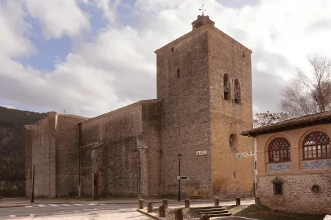 Vista general de iglesia de piedra con torre cuadrada en Aoiz.