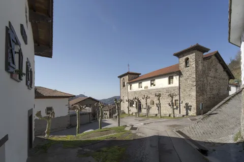 Parte delantera de una iglesia de piedra en Arano y vista de las calles de alrededor.