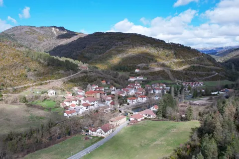 Vista aérea del pueblo de Esparza de Salazar rodeado de montañas boscosas y prados verdes en el valle pirenaico.