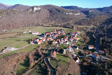 Vista aerea del pueblo de Garaioa rodeado de montes boscosos y praderas verdes en el Pirineo de Navarra.