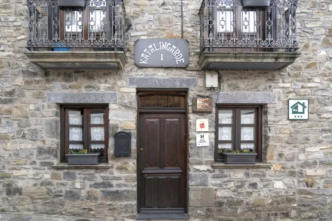 Fachada de piedra de casa rural Katalingarde en Isaba, Pirineo de Navarra, con balconadas de hierro forjado y puerta de madera.