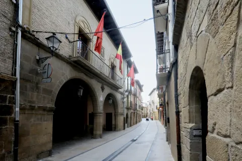 Calle de Lumbier con arcos de piedra, banderas y arquitectura tradicional.