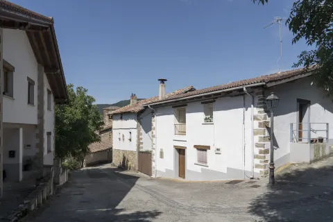 Calle de Olaibar con arquitectura tradicional de piedra y fachada blanca, en Plazaola-Sakana-Ultzamaldea.