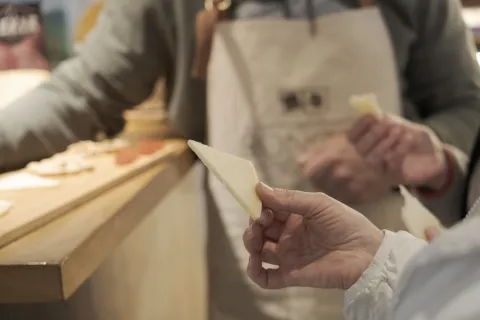 Mano sosteniendo queso fresco artesanal durante demostración de elaboración en Quesos Ekia, Pirineo de Navarra.