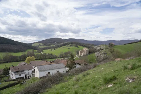 Casas dispersas en el valle de Odieta con iglesia al fondo y montañas verdes.