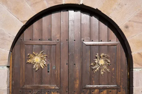 Puerta de madera de arco con dos eguzkilores y herrajes decorativos en Valle de Anue, arquitectura tradicional navarra.