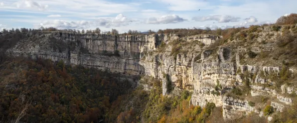 Cortados calizos verticales de la Sierra de Urbasa con bosque caducifolio en otoño bajo cielo nublado.