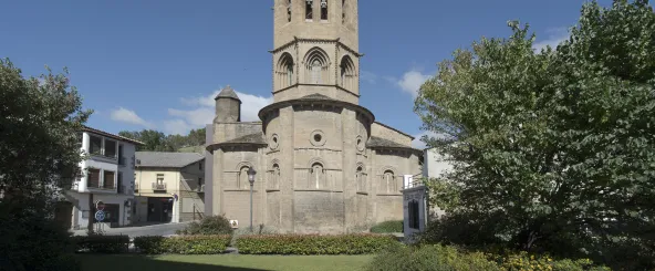 Iglesia Santa María la Real de Sangüesa con torre románica gótica de piedra sillar, enmarcada por vegetación.
