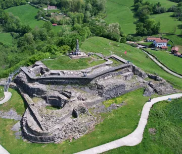 The ruins of Amaiur Castle in the lush Baztan Valley, featuring stone walls and a memorial.