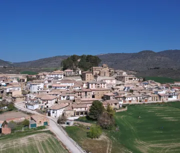 Pueblo de Eslava con iglesia, casas de piedra y campos cultivados alrededor.