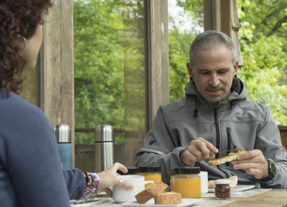 Dos turistas comparten desayuno con productos locales en terraza de Basoa Suites, Ultzama, rodeados de bosque.