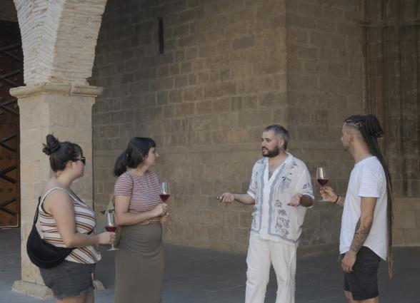 Visitantes catando vino de bodega Azpea de Lumbier frente a pared de piedra.