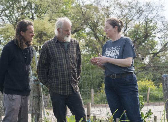 Visitantes reciben explicación de una de las propietarias de Curly Creek Ranch mientras miran la huerta y el cultivo.
