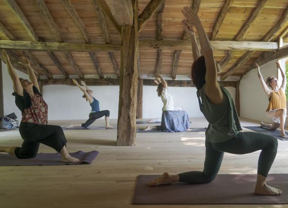 Clase de yoga en interior de una casa con vigas de madera tradicional, parte de la experiencia de Ekino Aukera.