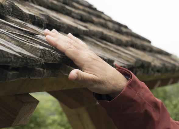 Mano tocando estructura de madera envejecida de tejado tradicional pirenaico navarro, parte de la experiencia Lorentx.