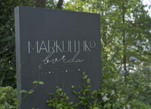 Cartel de entrada a Markulluko Borda, alojamiento rural en Baztan-Bidasoa, rodeado de vegetación verde.
