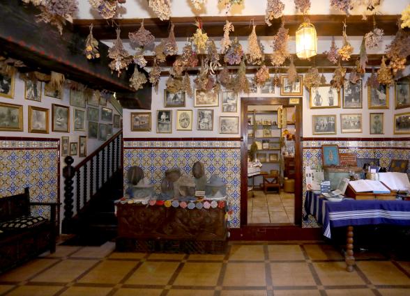 Interior de museo de apicultura de Ezkurdi, con paredes llenas de fotografias colgadas y flores secas en el techo.