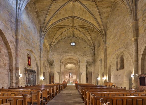 Interior de la nave central del Monasterio de Leyre con bóvedas de crucería, columnas de piedra y bancos de madera.