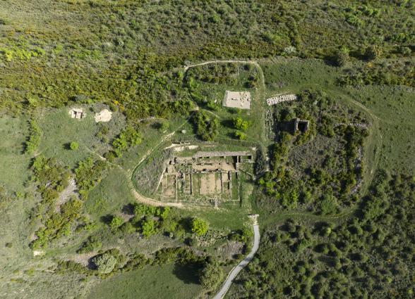 Vista aerea de las ruinas de Santa Criz de Eslava rodeadas de arboles y vegetacion, sendero y construcciones anexas.
