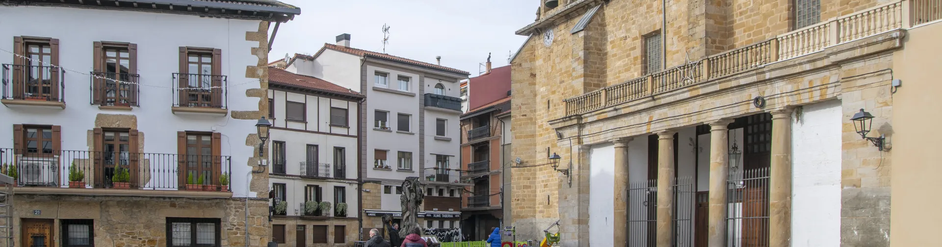 Calle empedrada del casco antiguo de Alsasua con edificios de piedra y la iglesia a un lado.