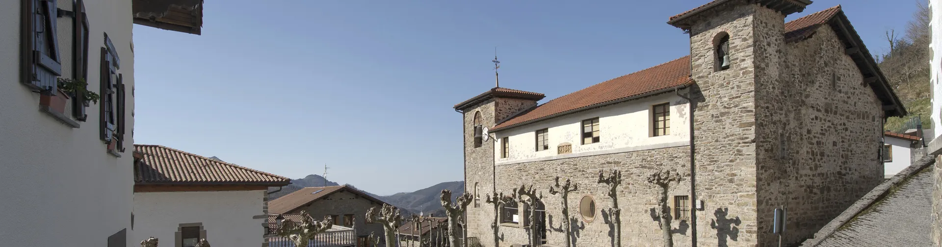 Parte delantera de una iglesia de piedra en Arano y vista de las calles de alrededor.