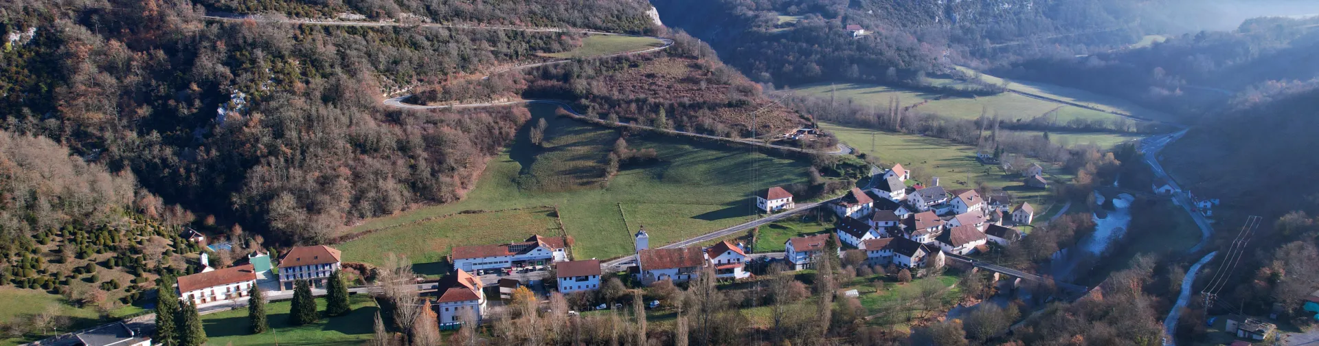 Vista aerea de Aribe con rio, montes boscosos y casas tradicionales dispersas en el valle pirenaico.