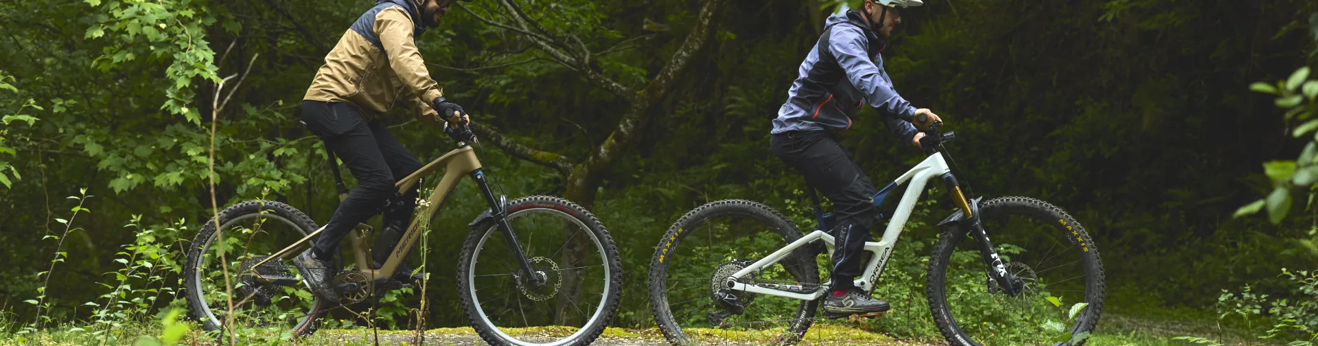 Dos ciclistas en sendero BTT entre bosque atlántico con arroyo y puente con musgo en Lesaka, Baztan-Bidasoa.