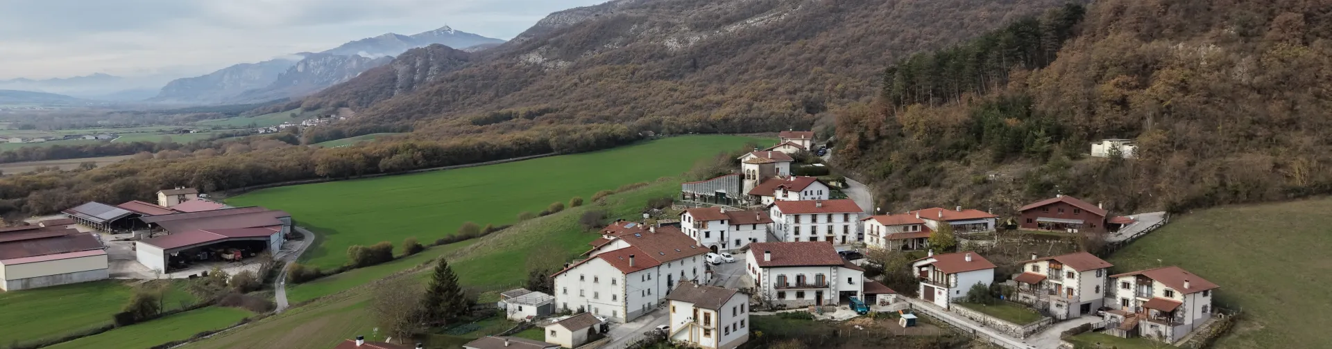 Vista aérea de pueblo de Arakil con iglesia campanario en valle verde pirenaico rodeado de montes.