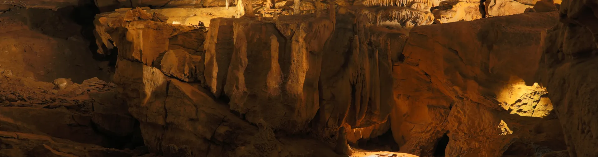 Interior de las Cuevas de Urdax con estalactitas iluminadas en tonos dorados y formaciones rocosas características.