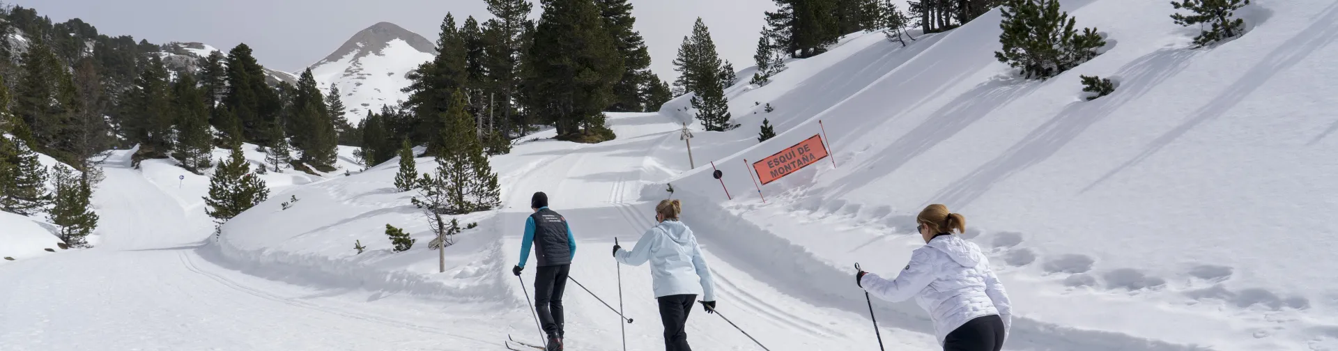Tres personas subiendo una cuesta de nieve con esquis en la experiencia turistica de Katalingarde.