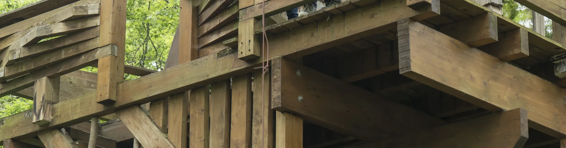 escaleras y plataforma de madera, donde dos turistas suben una cesta de mimbre mediante una polea.