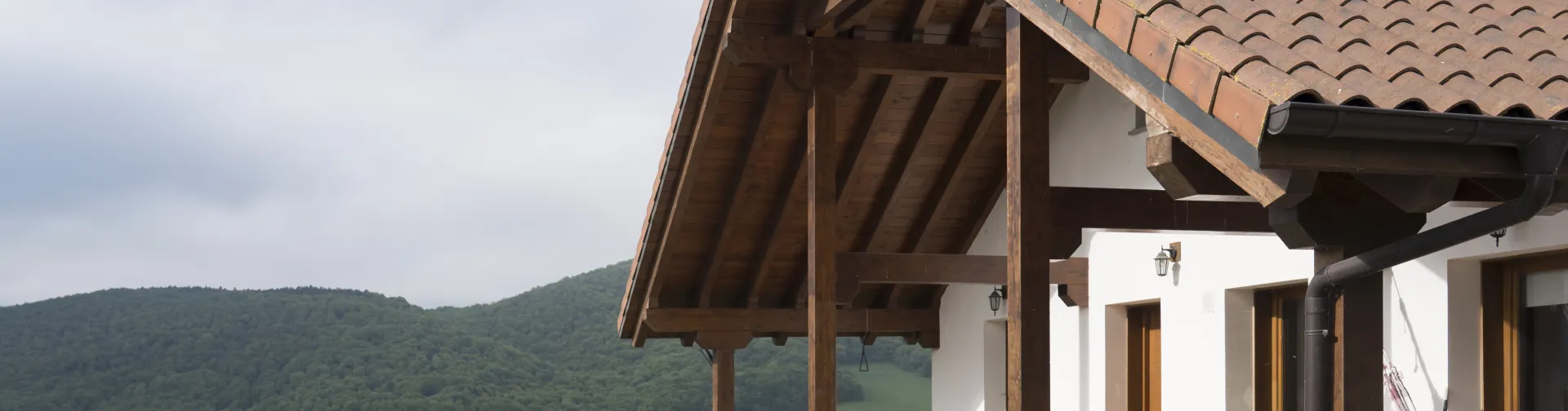 Porche de madera y vistas al valle de Ultzama, con prados verdes y monte boscoso.