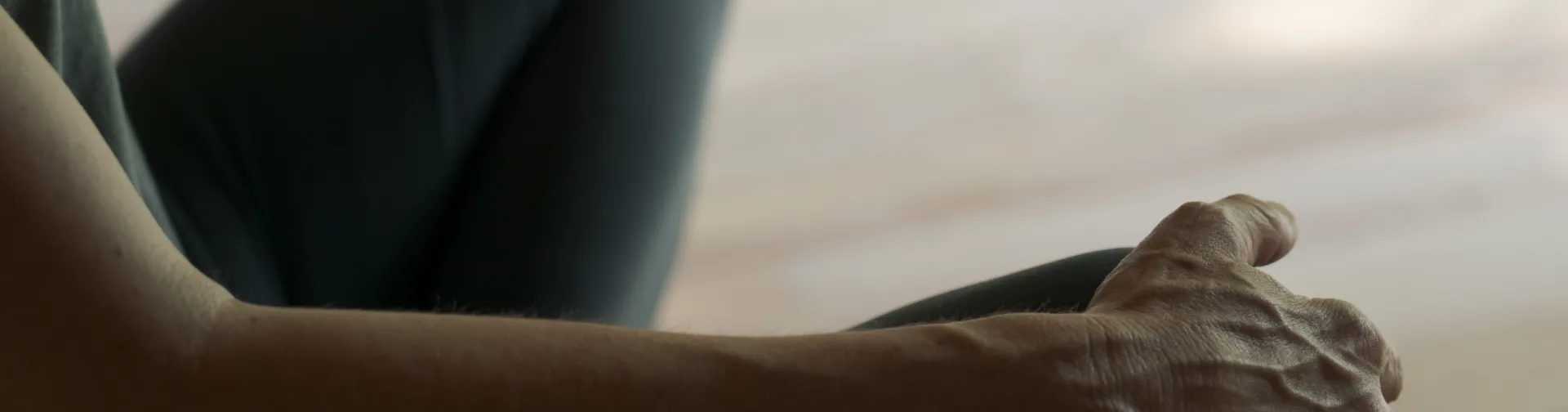 Detalle de manos sobre las rodillas de persona sentada practicando yoga en la experiencia de Ekino Aukera.