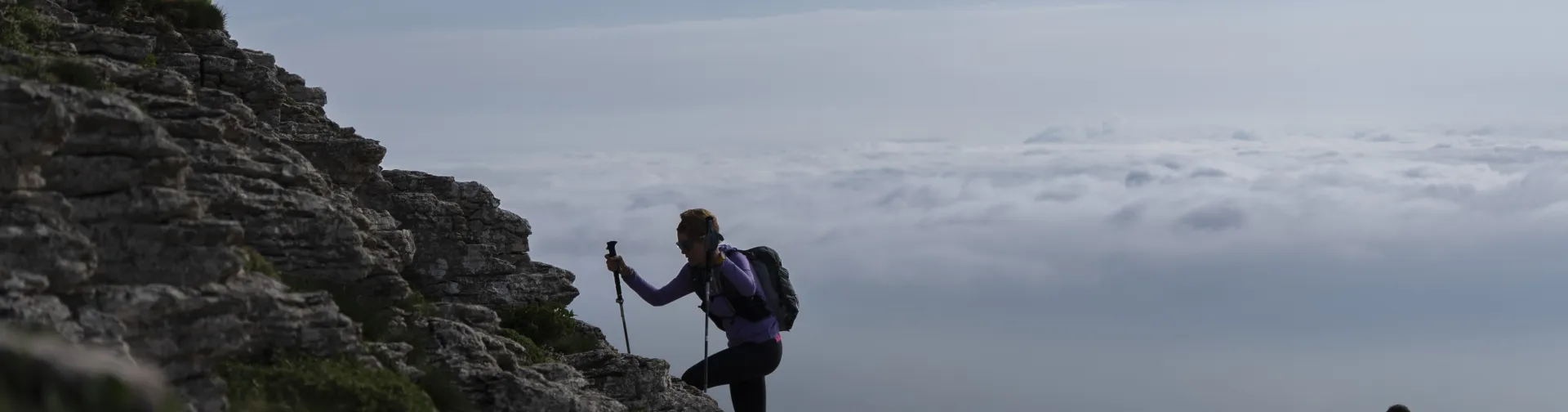 Senderistas haciendo treking y subiendo un monte reocoso con palos, en Plazaola-Sakana-Ultzamaldea