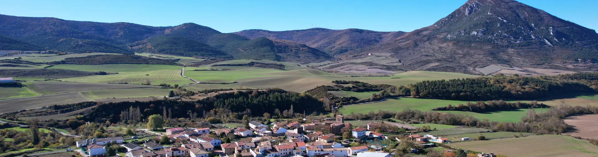 Vista aérea de Ibargoiti con campos de cultivo, bosques y montes del Prepirineo al fondo.