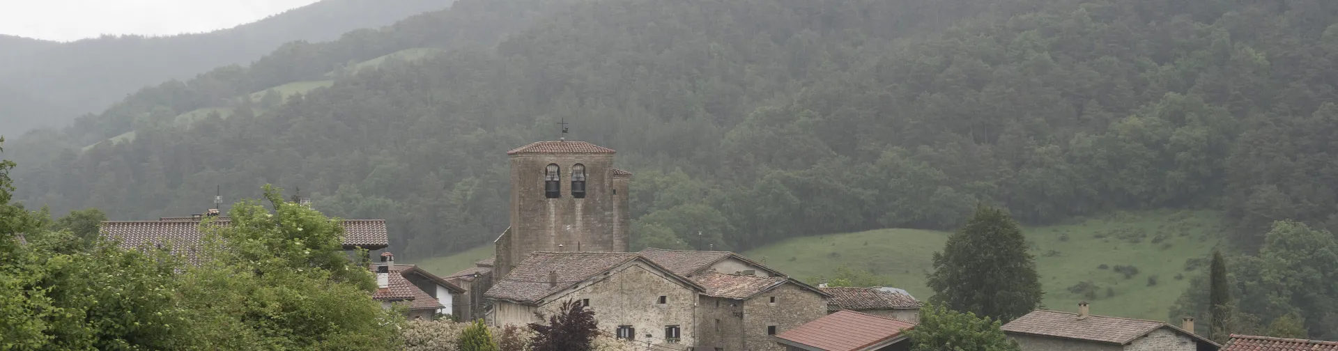 Vista genernal de  Ilurdoz en Pirineo navarro, rodeado de monte con bosque denso y niebla matutina sobre valle.