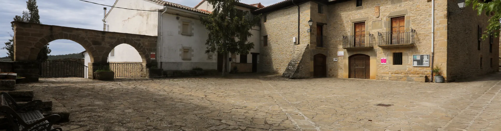 Plaza de Leache con casas de piedra arenisca y arcos de piedra.
