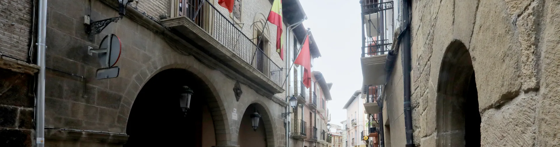 Calle de Lumbier con arcos de piedra, banderas y arquitectura tradicional.
