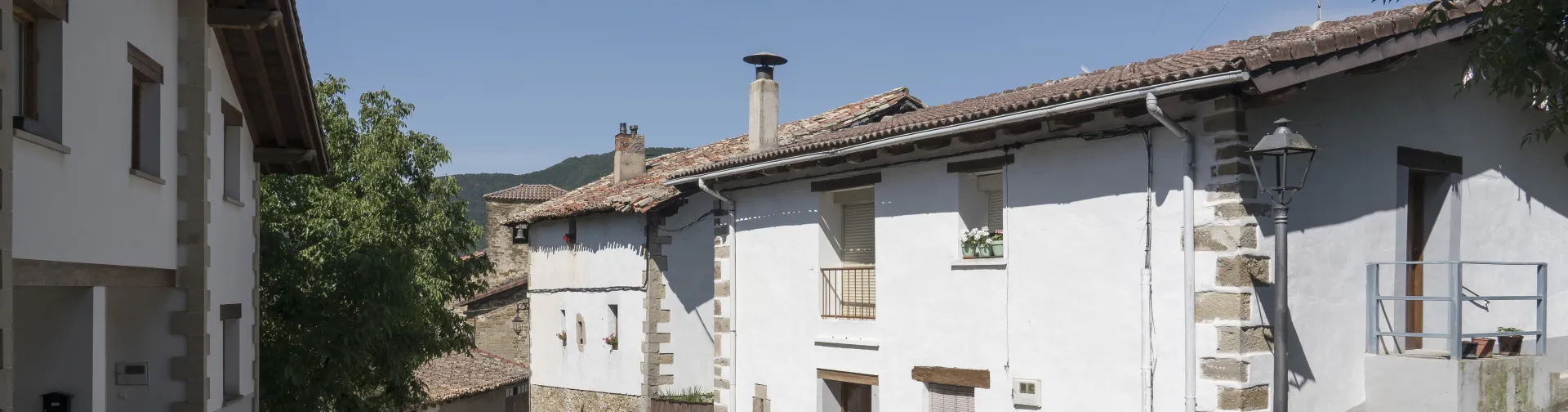 Calle de Olaibar con arquitectura tradicional de piedra y fachada blanca, en Plazaola-Sakana-Ultzamaldea.