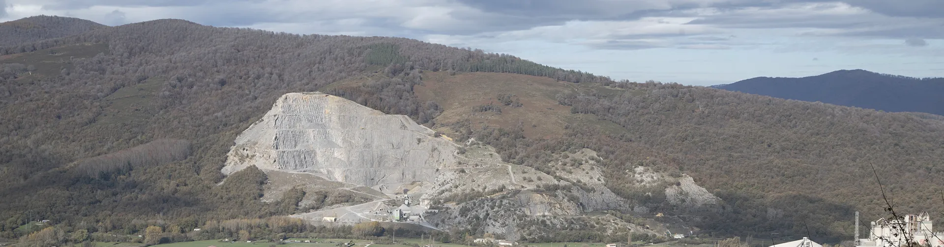 Olaztiren bista panoramikoa. Atzealdean, basoz inguratuta dagoen kare zuriko harrobia dauka.