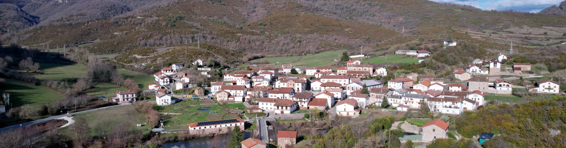 Vista aerea del pueblo de Oroz-Betelu rodeado de montes, casas con tejados rojos y prados verdes.