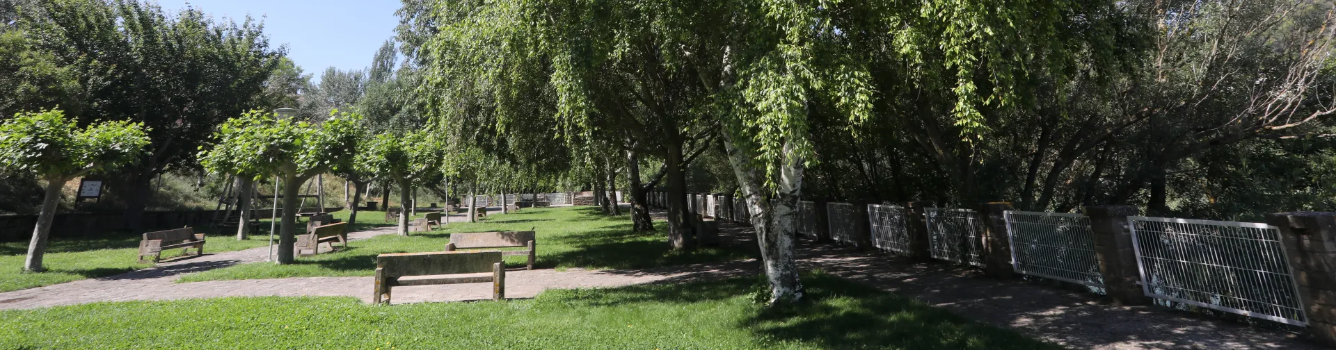 Paseo Cantolagua en Sangüesa con bancos de piedra y jardín junto al río Aragón.