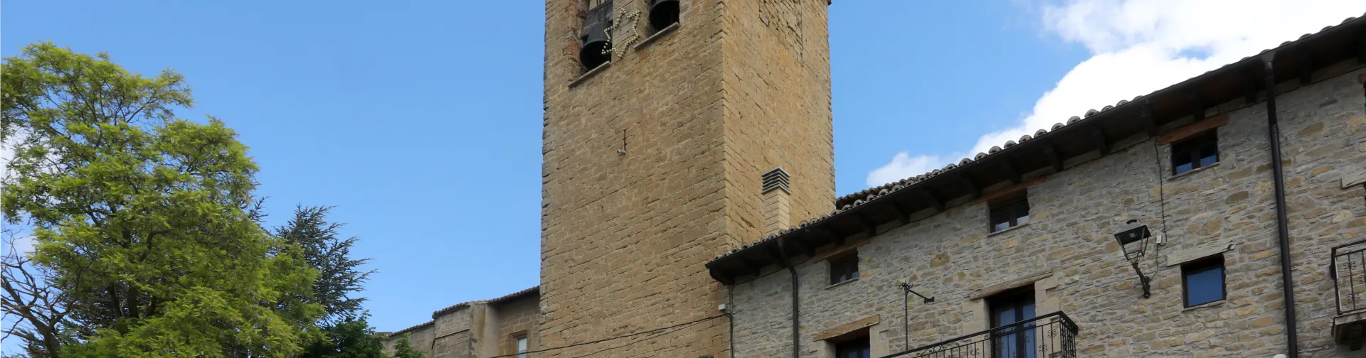 Iglesia de San Vicente en Sada con torre de piedra arenisca y campanario.