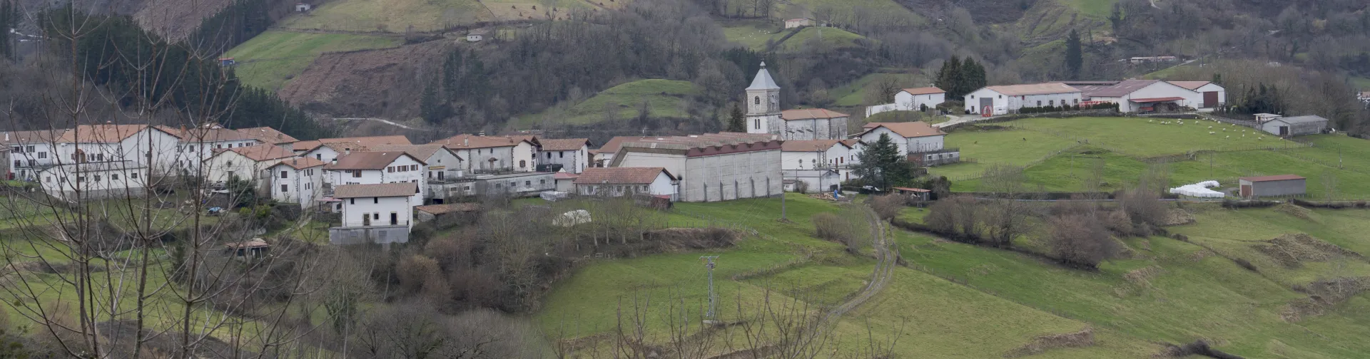 Vista panorámica aérea del valle de Saldias con el pueblo rodeado de montañas verdes y espacios de cultivo.
