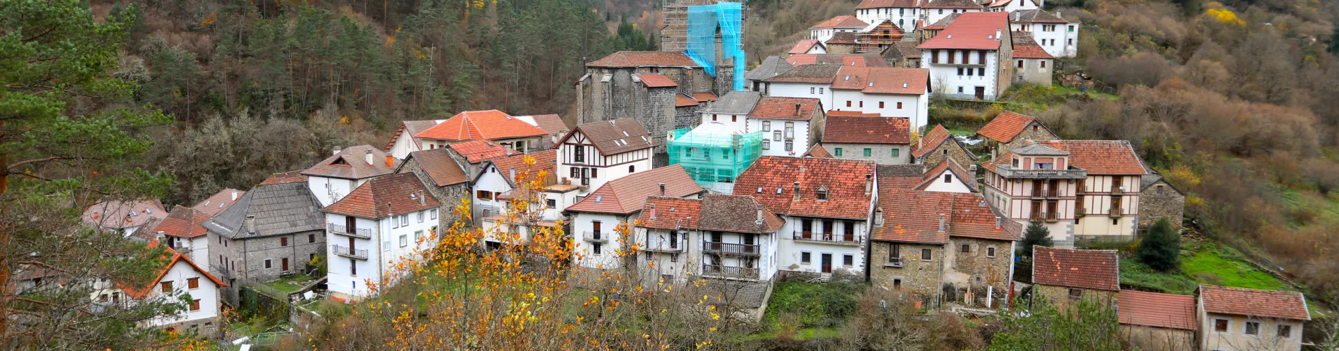 Uztarroz herria, Pirinioetako haranean, teilatu gorriko etxe tradizionalekin, harrizko elizarekin eta mendi basoekin, udazkenean.