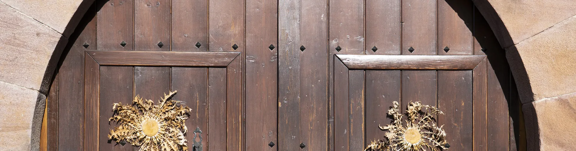 Puerta de madera de arco con dos eguzkilores y herrajes decorativos en Valle de Anue, arquitectura tradicional navarra.